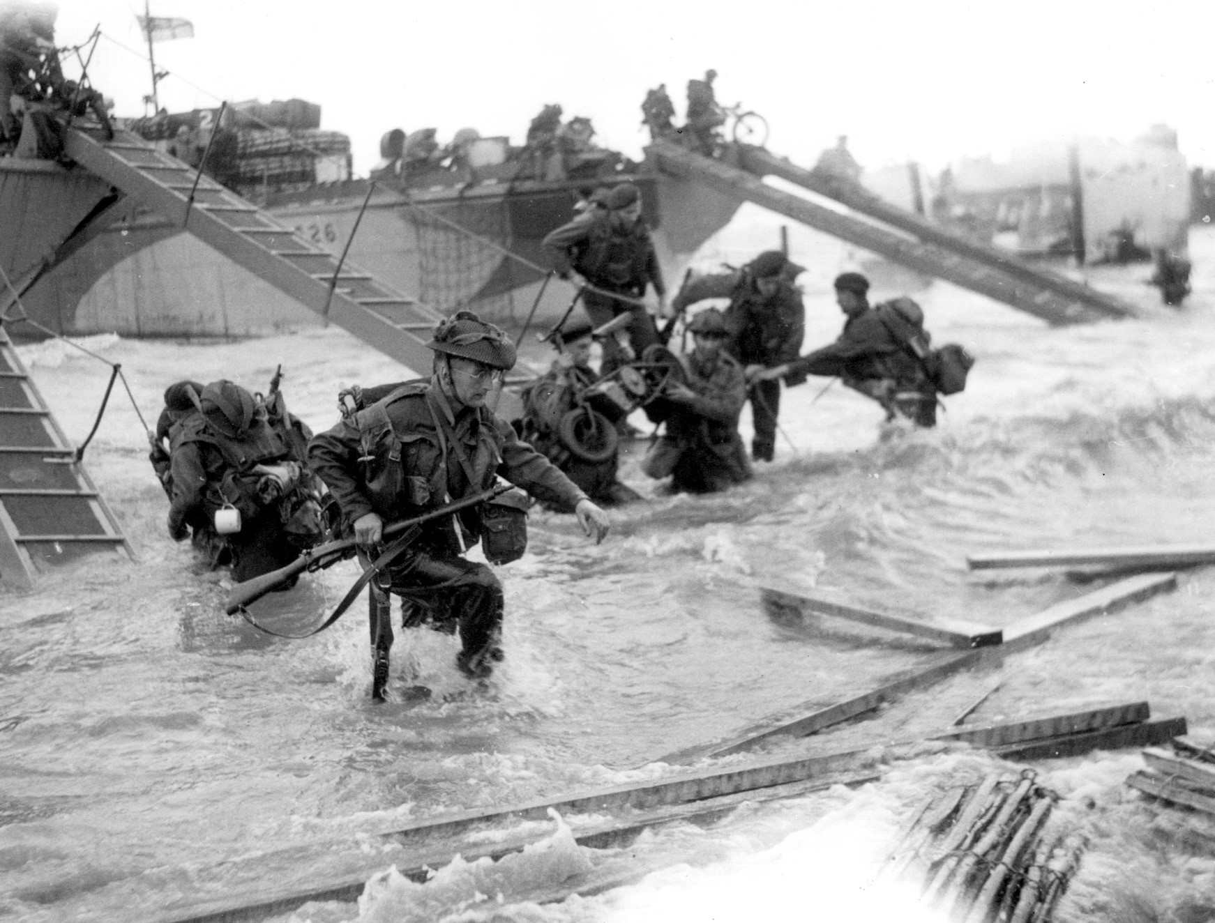 Soldiers wade through waves lapping at their knees in order to reach the Normandy beaches.